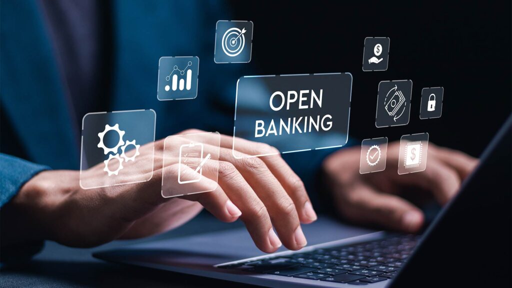 Mãos digitando em um notebook com ícones digitais flutuantes representando serviços financeiros e a palavra 
