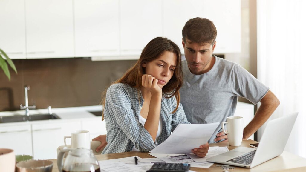 Casal analisando documentos financeiros em casa, representando a busca por soluções como o crédito pessoal para organizar o orçamento.