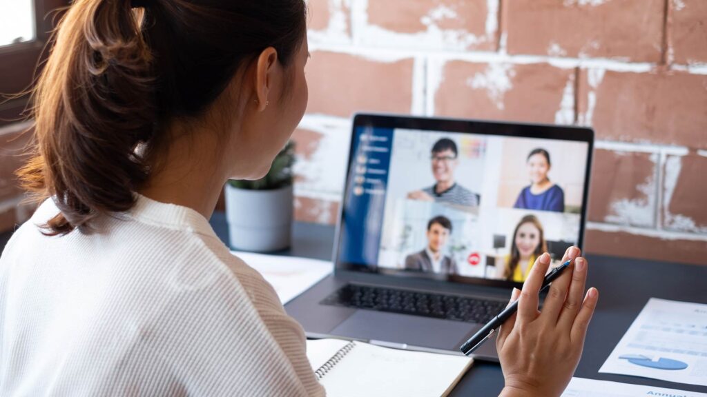 Mulher participa de videoconferência com equipe, demonstrando práticas de atendimento remoto eficiente.