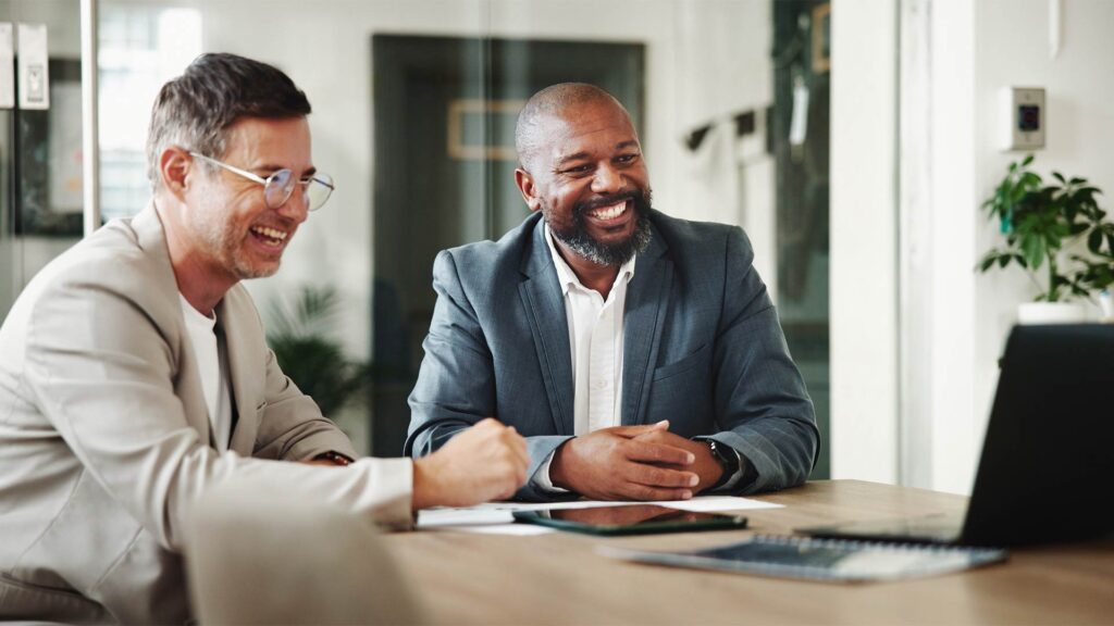 Dois profissionais sorridentes em uma reunião, transmitindo confiança e empatia no atendimento ao cliente.