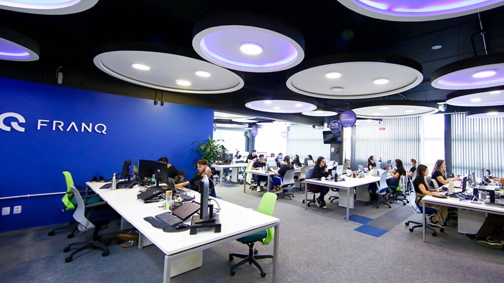Ambiente colaborativo da fintech Franq com profissionais trabalhando em um escritório moderno e tecnológico.