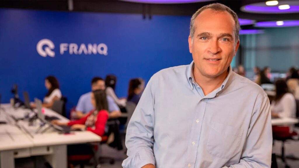 CEO da fintech Franq no escritório, com equipe ao fundo, representando inovação na distribuição de produtos financeiros no Brasil.