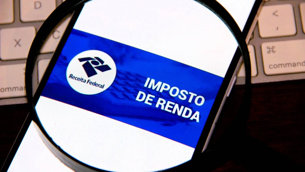 Tela de celular exibindo o logotipo da Receita Federal e a frase “Imposto de Renda” ampliada por uma lupa.