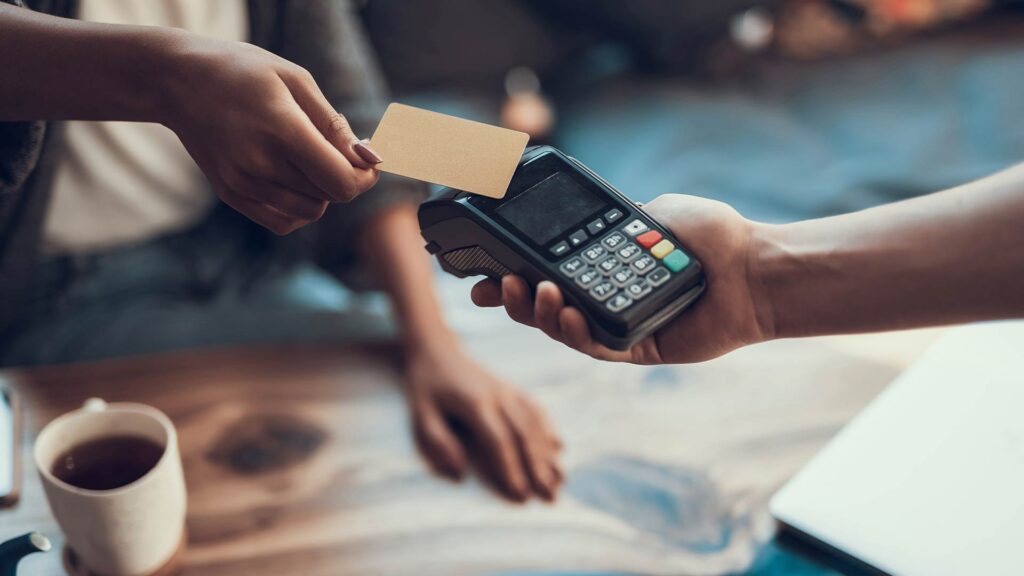Pessoa realizando pagamento por aproximação com cartão de crédito, representando operações que podem ser utilizadas na antecipação de recebíveis.