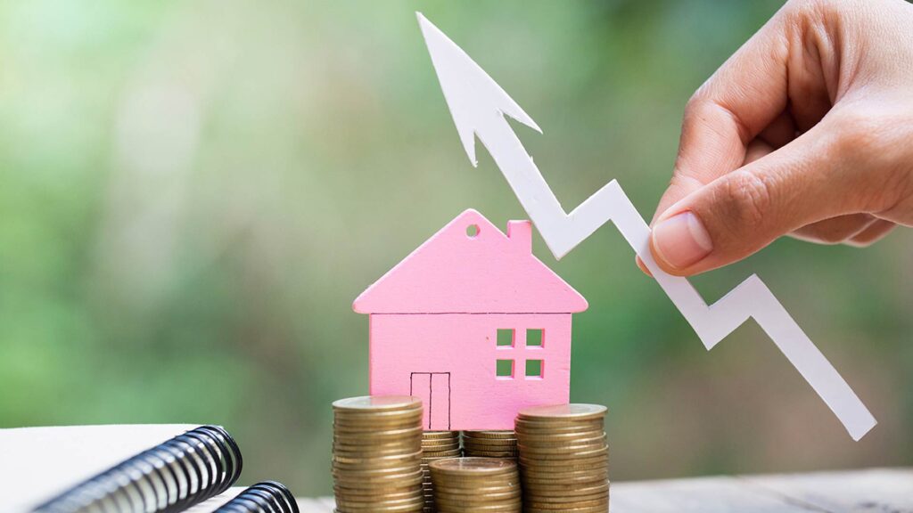 Casa em miniatura rosa posicionada sobre pilhas de moedas, com uma seta branca apontando para cima, simbolizando valorização e crescimento financeiro por meio de empréstimo com garantia de imóvel.