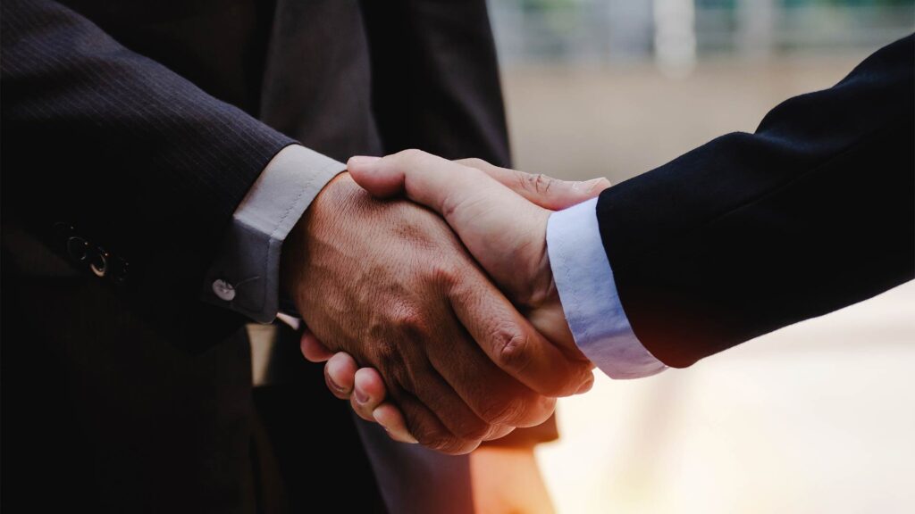 Aperto de mãos entre dois profissionais, simbolizando o fechamento de um acordo sobre linhas de crédito.