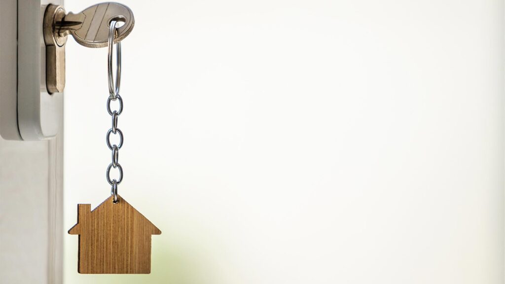 Chave na fechadura com chaveiro em forma de casa, simbolizando o uso do imóvel como garantia em home equity.