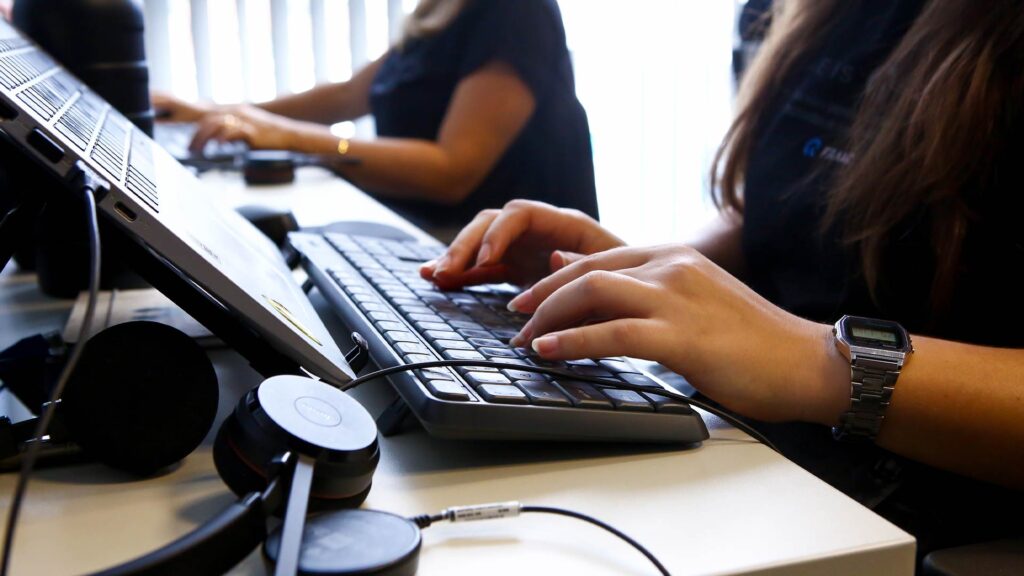 Pessoa digitando em teclado de computador enquanto preenche informações no sistema, em contexto relacionado ao Imposto de Renda.