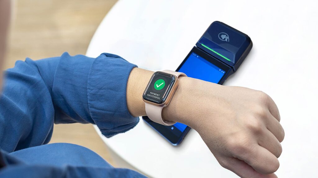 Pagamento realizado com smartwatch, representando a evolução do comportamento do consumidor em direção a soluções financeiras mais rápidas e tecnológicas.
